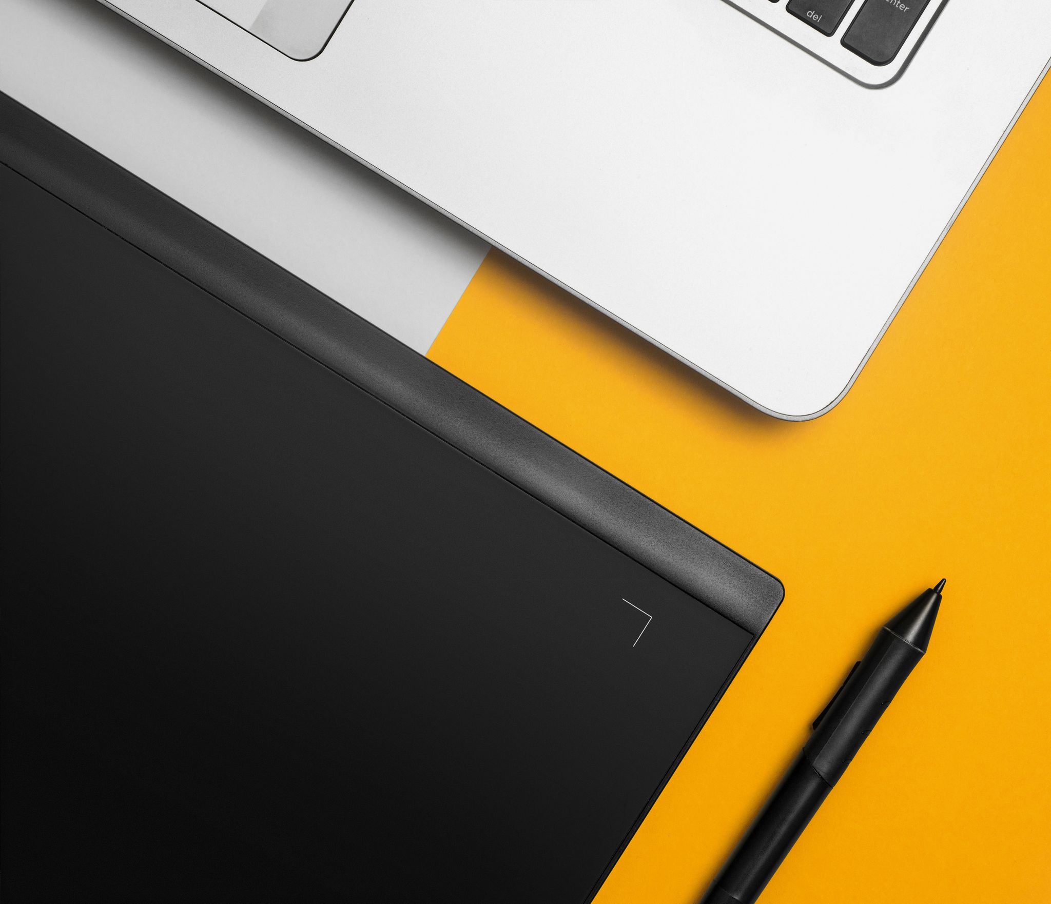 Overhead view of a laptop and graphics tablet on a colorful desk setup.